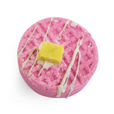 Pink bath bomb with yellow center and white drizzle on a white background