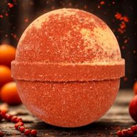 Orange bath bomb on a wooden surface with oranges in the background