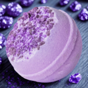 Purple bath bomb with glitter on a dark surface with purple rhinestones.