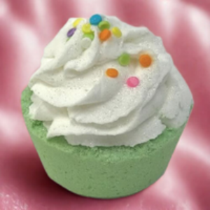 Green bath bomb with white whipped cream and colorful sprinkles on a pink background