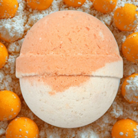 Bath bomb with a gradient from orange to white, surrounded by small oranges on a light background