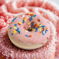 Donut with colorful sprinkles on a pink background