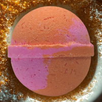Round pink and orange bath bomb on a glittery surface