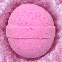 Pink bath bomb with raspberry pieces on a pink textured background