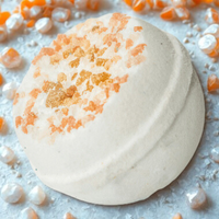 Bath bomb with orange bath salts on a light gray background