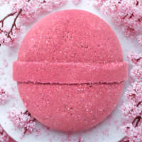 Pink bath bomb with cherry blossoms on a light background