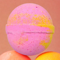 Colorful bath bomb with a pink top and yellow text on a brown background
