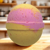 Bath bomb with pink and yellow layers on a wooden surface