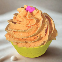 Cupcake with orange frosting and a pink flower on a white background