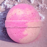 Pink bath bomb with a gold stripe on a textured surface