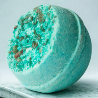 Green bath bomb with textured surface on a light gray background